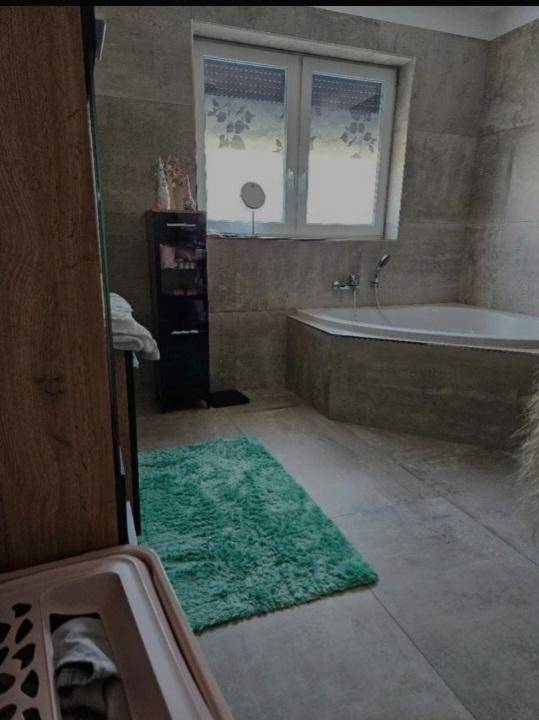 Modernes Badezimmer mit Eckbadewanne, großen Fliesen und Fenster für Tageslicht.