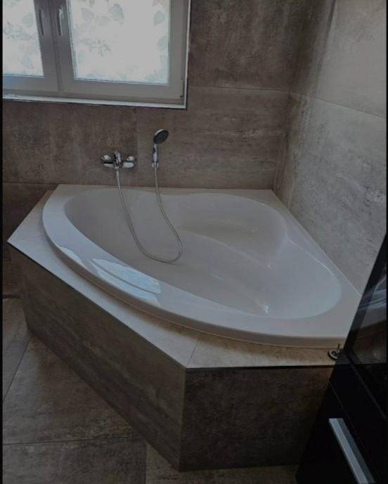 Detailansicht der modernen Eckbadewanne im gefliesten Badezimmer.