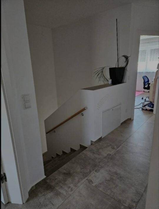 Treppenabgang mit Holzgeländer und praktischem Stauraum unter der Treppe.