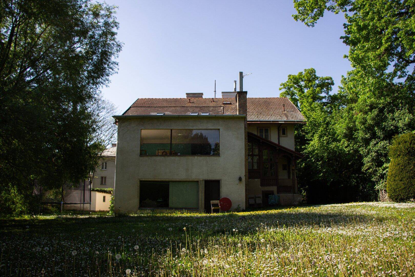 Weitläufiger Blick auf die Rückseite des Hauses und den großen, sonnigen Garten.