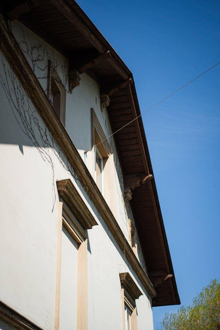 Detailaufnahme der Fassade mit Holzdachüberstand und dekorativen Elementen unter blauem Himmel.