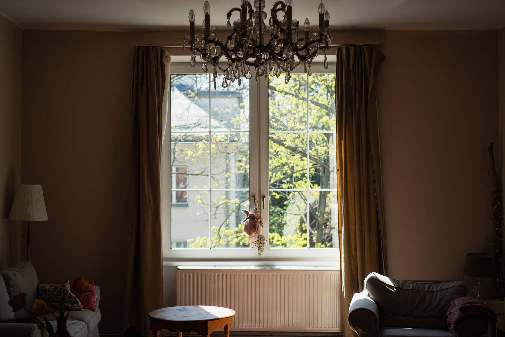 Helles Wohnzimmer mit großem Fenster, Kronleuchter und klassischer Einrichtung.