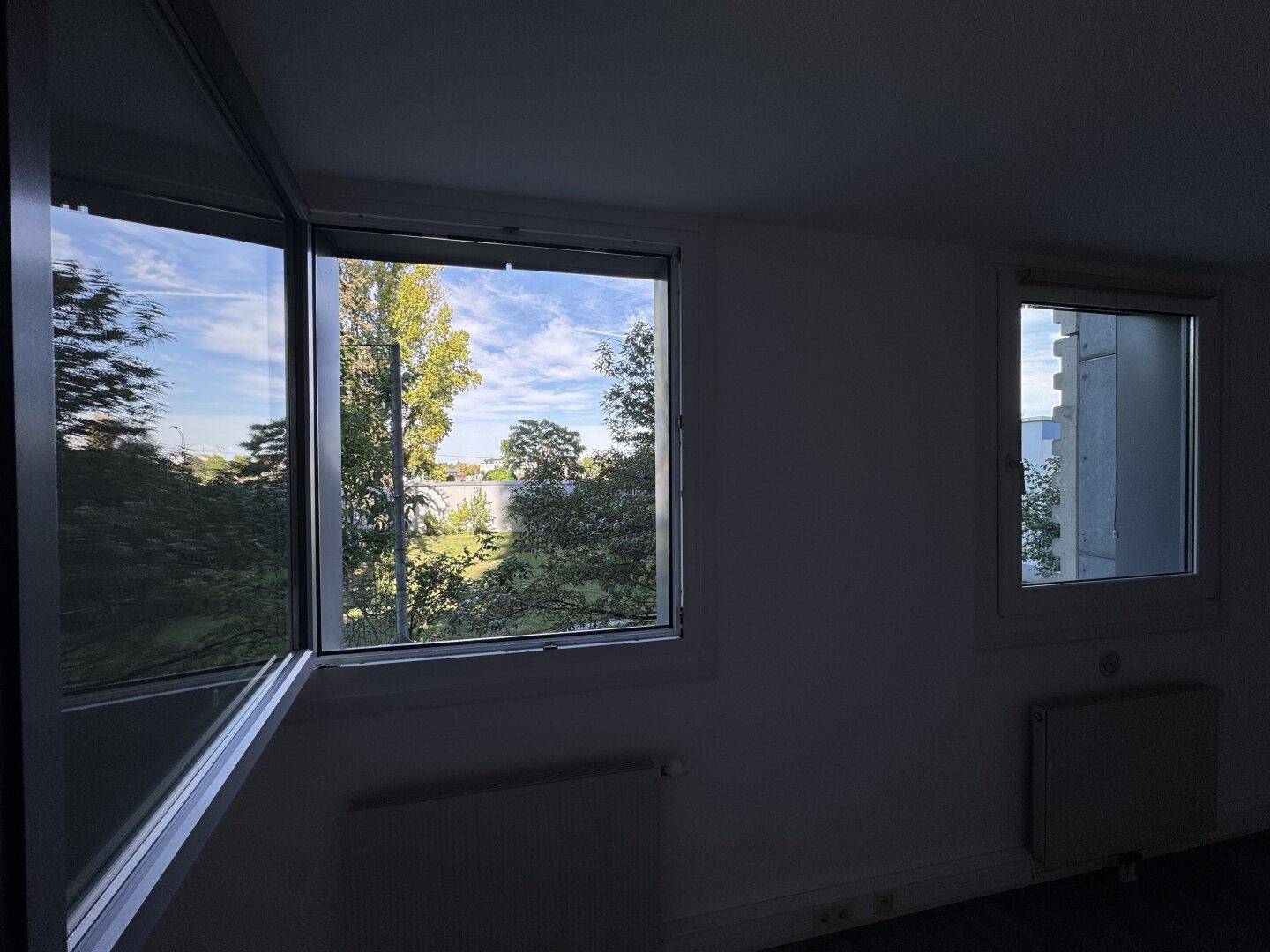 Fenster mit Blick auf grüne Bäume und den Fluss, die viel natürliches Licht in den Raum bringen.
