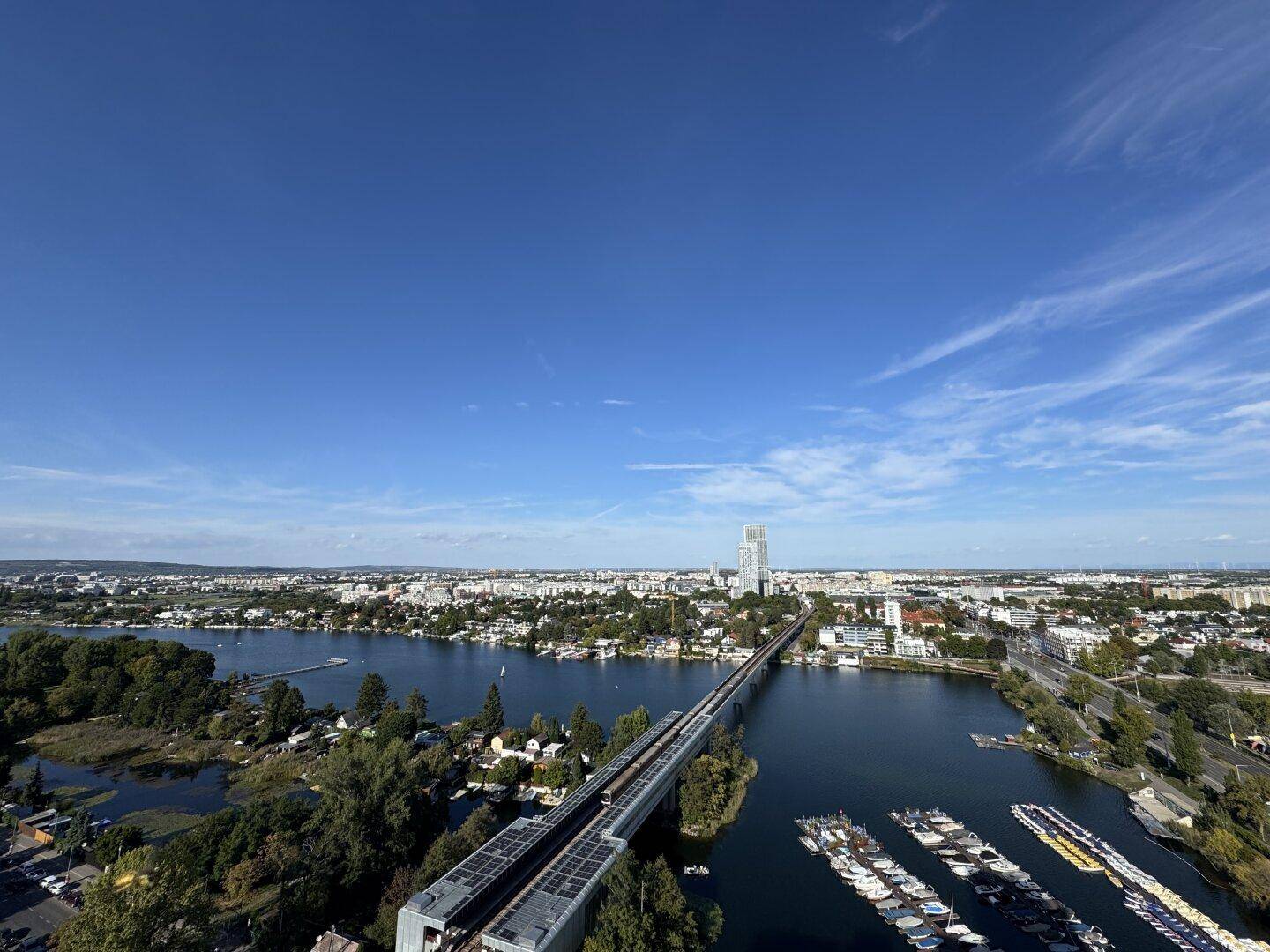 Panoramablick auf die Stadt, den Fluss mit Brücke und Boote unter einem klaren blauen Himmel.