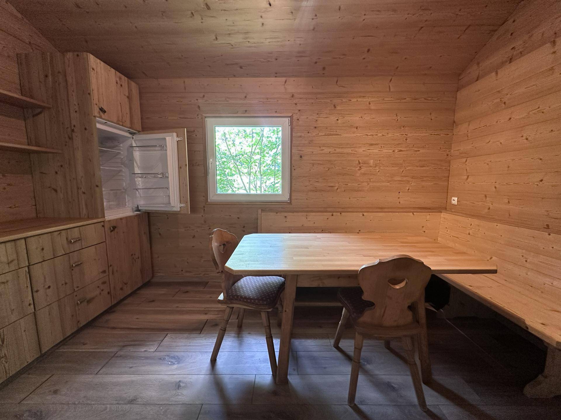 Heller Essbereich mit Holztisch, Eckbank und Blick durch das Fenster in die Natur.