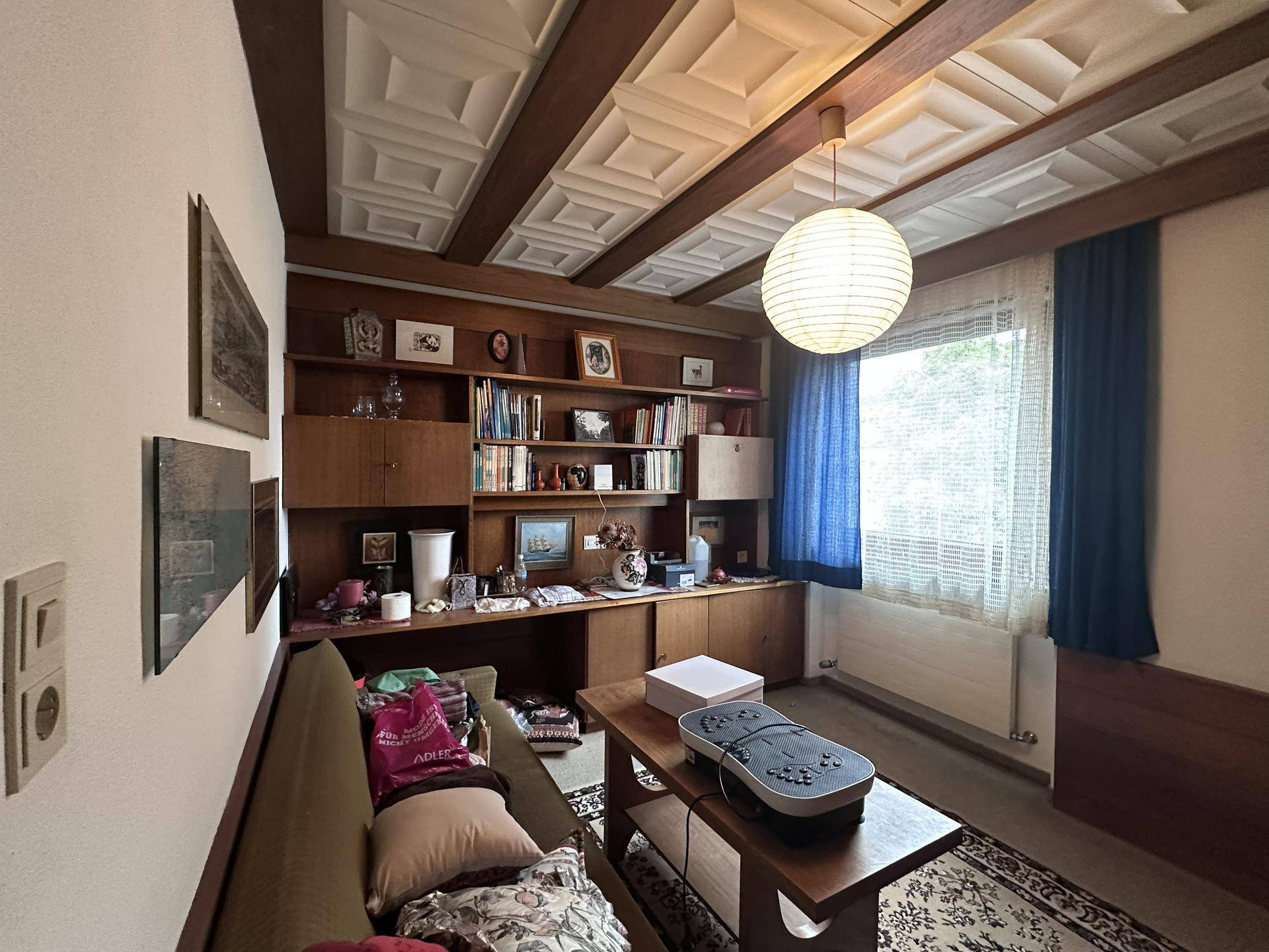 Arbeitszimmer mit Holzdecke, Einbauschränken und großem Fenster.
