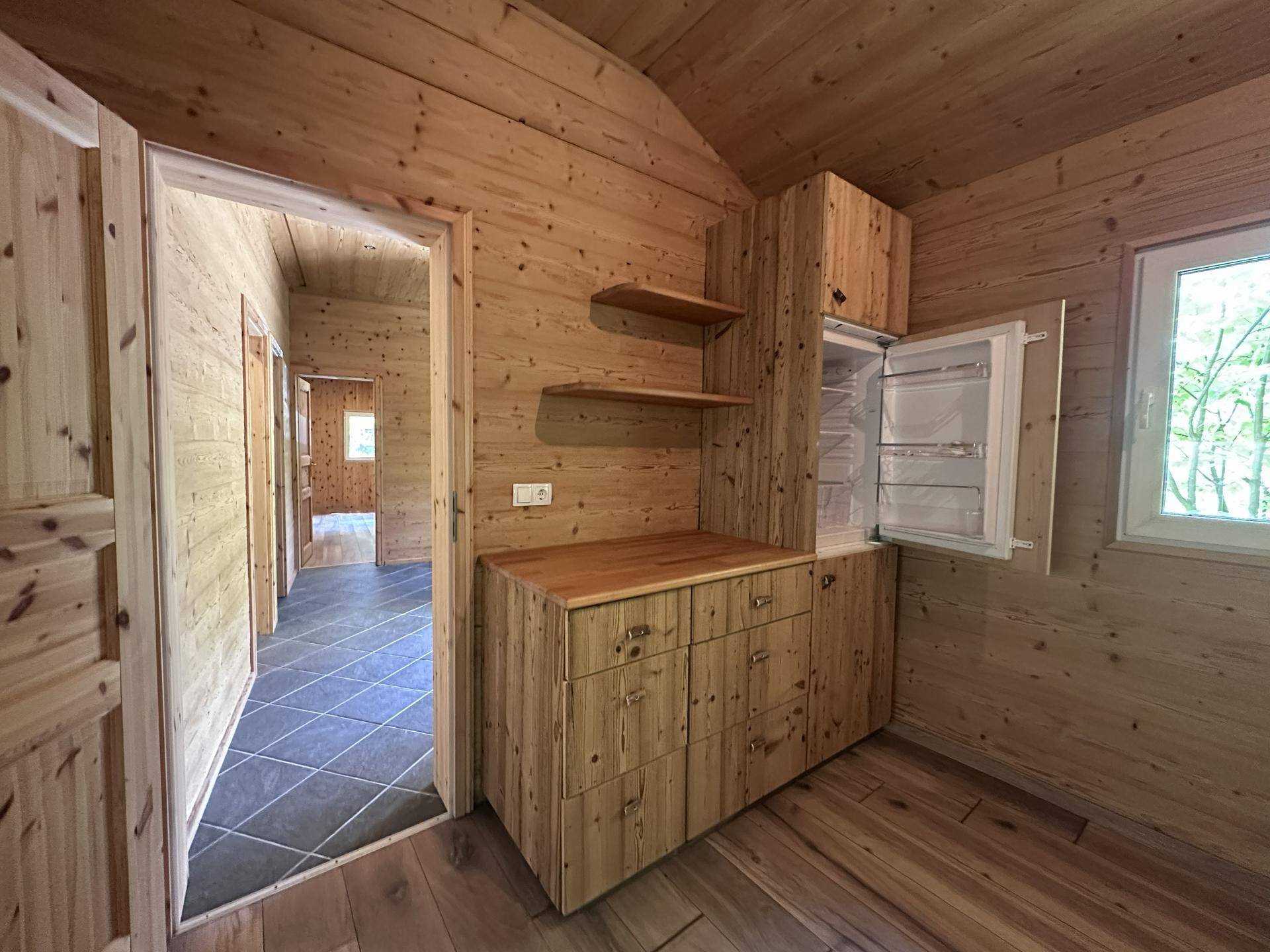 Heller Flur mit Holzvertäfelung, integriertem Kühlschrank und Zugang zu weiteren Räumen.