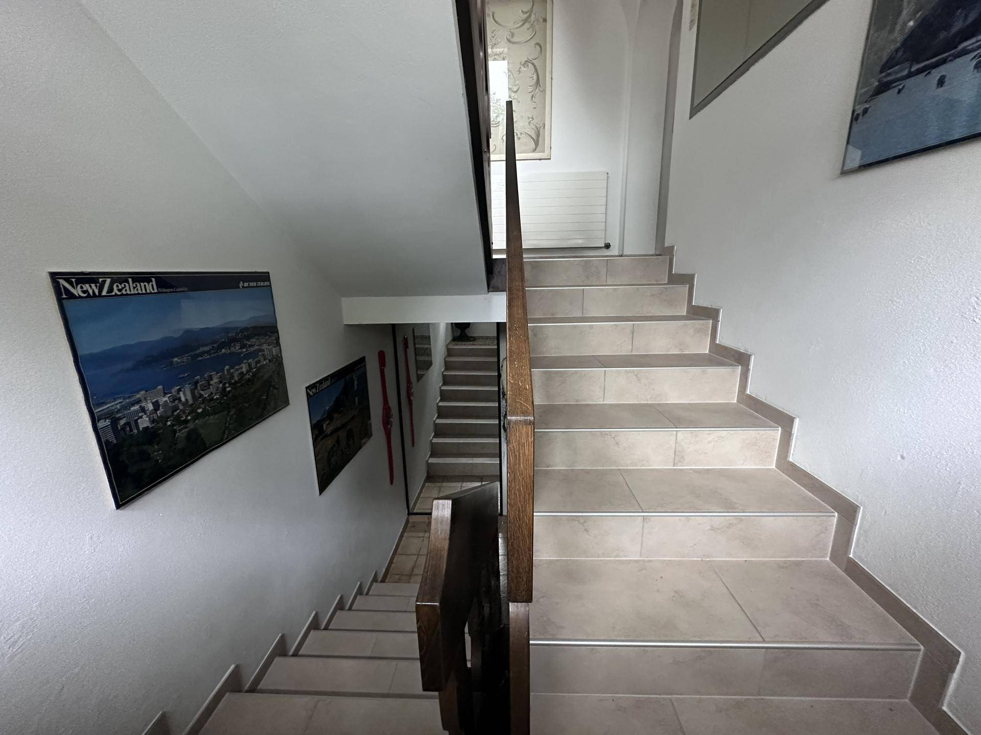 Heller Treppenaufgang mit Fliesenstufen und schlichten weißen Wänden.