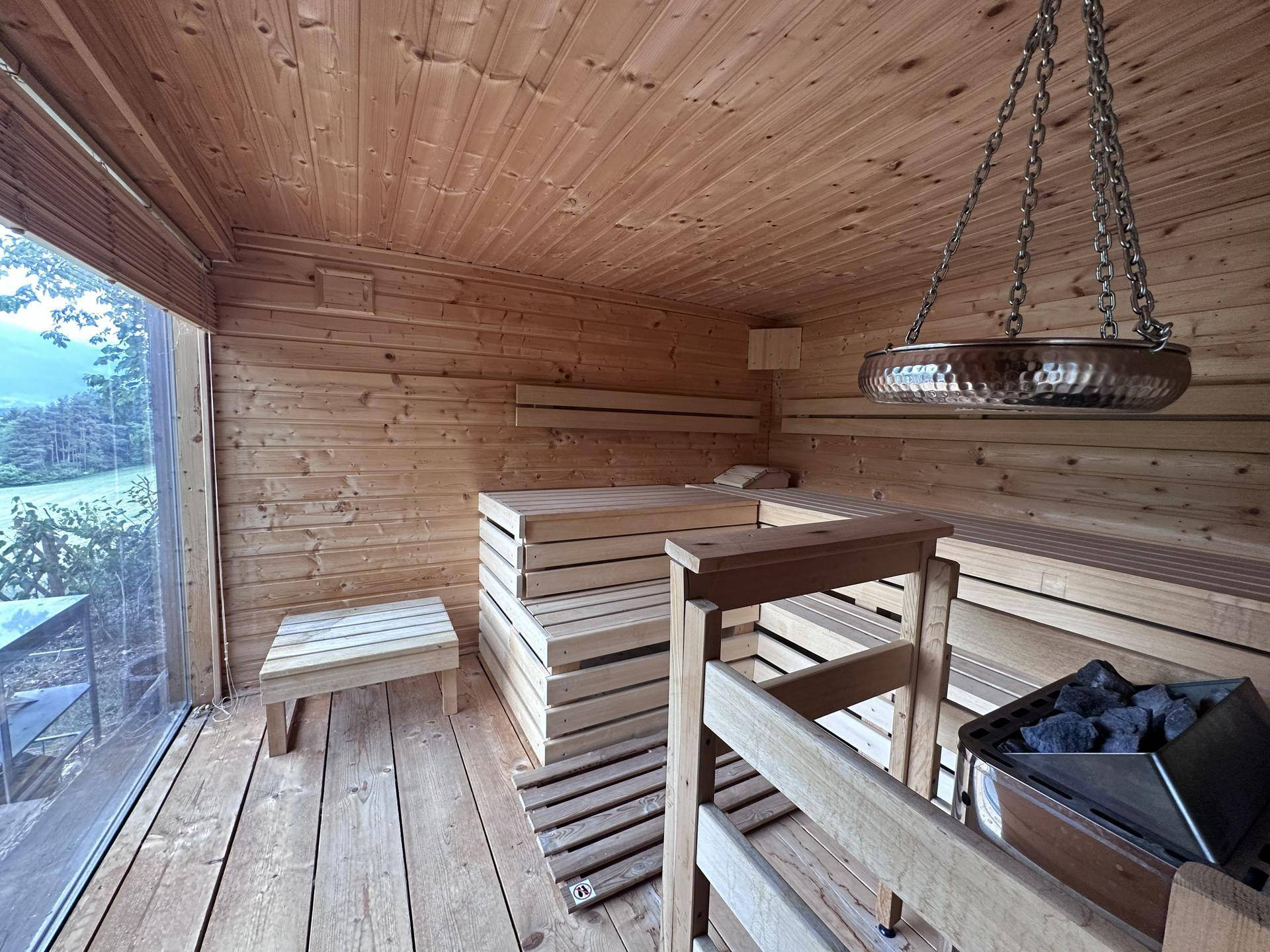 Moderne Holzsauna mit großen Fenstern und Blick auf die umliegende Natur.