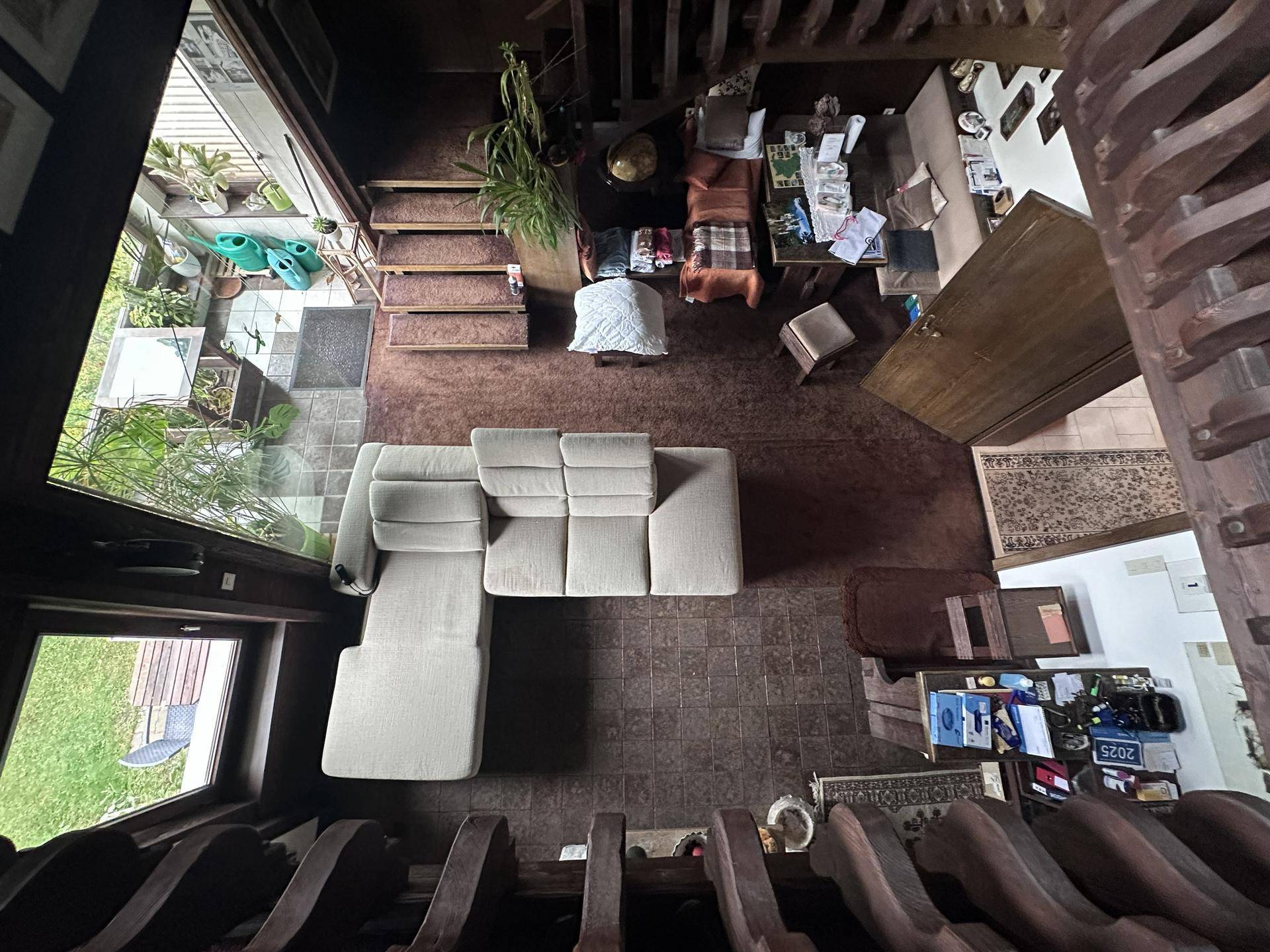 Blick von oben auf ein Wohnzimmer mit hellem Sofa und Zugang zu einem Außenbereich.