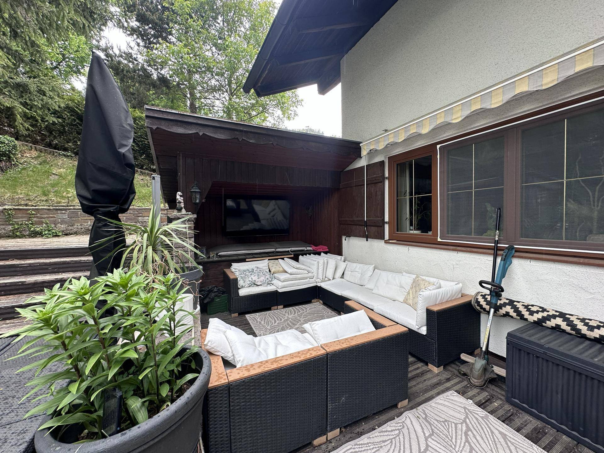 Überdachte Terrasse mit bequemen Lounge-Möbeln und Blick ins Grüne.