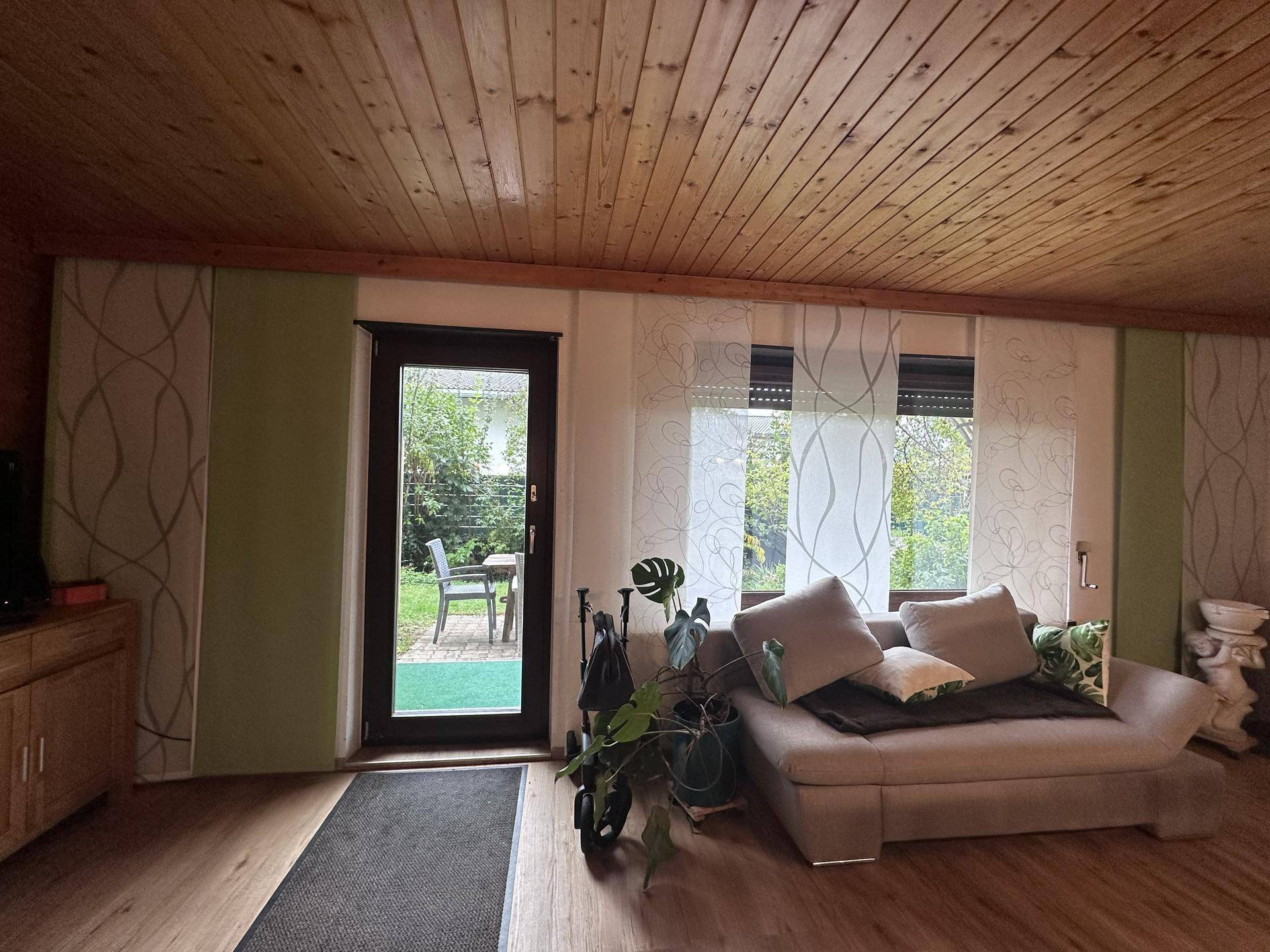 Heller Wohnbereich mit Holzboden, Zugang zum Garten und großen Fenstern.