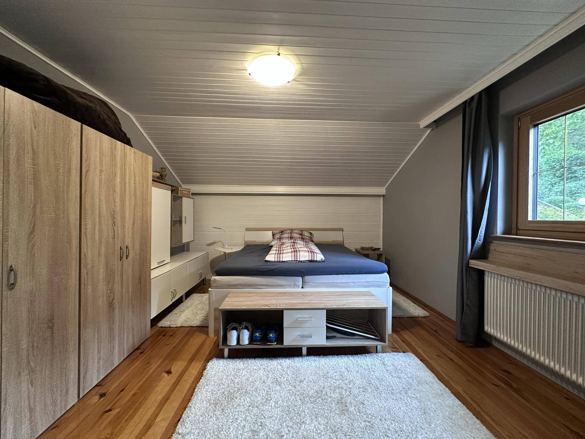 Gemütliches Schlafzimmer im Dachgeschoss mit Holzboden, Dachschräge und großem Kleiderschrank.