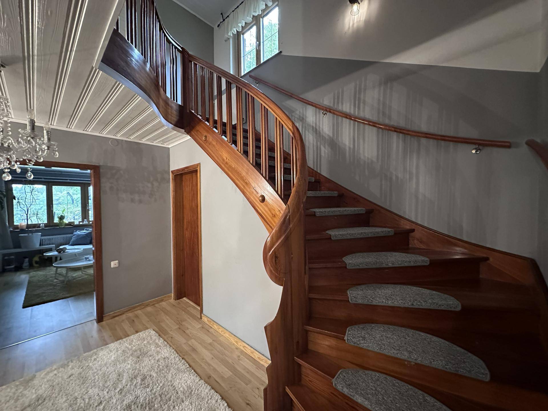 Elegantes Treppenhaus mit geschwungener Holztreppe und Holzboden, führt zu den oberen Etagen.