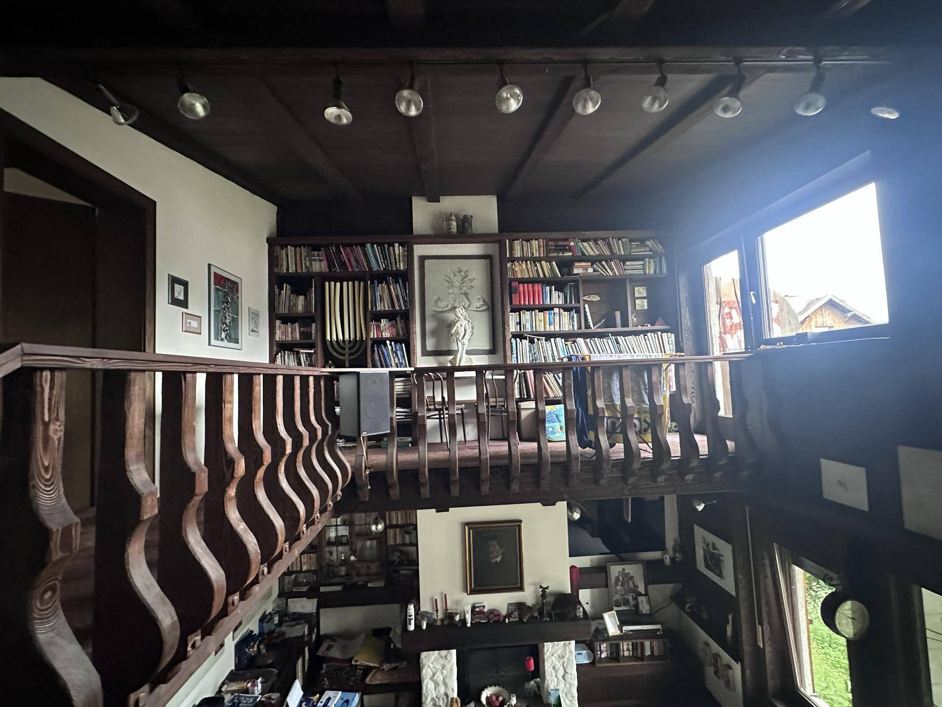 Offener Wohnbereich mit Galerie, Bücherregalen und Holzbalkendecke.