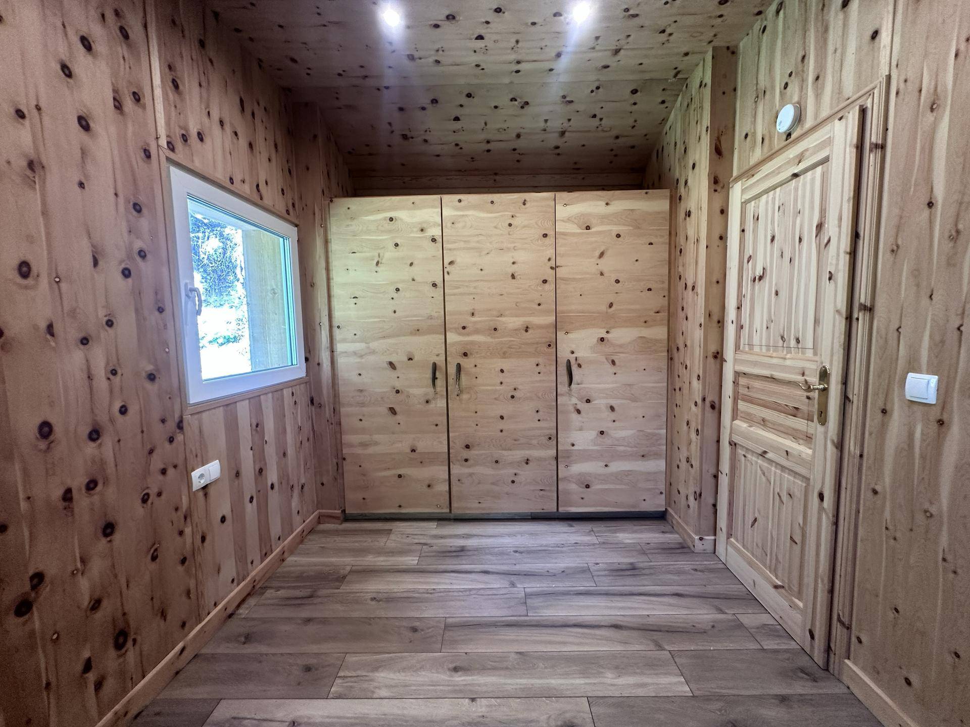 Gemütliches Zimmer mit Holzwänden, Holzdecke und integrierten Holzschränken.