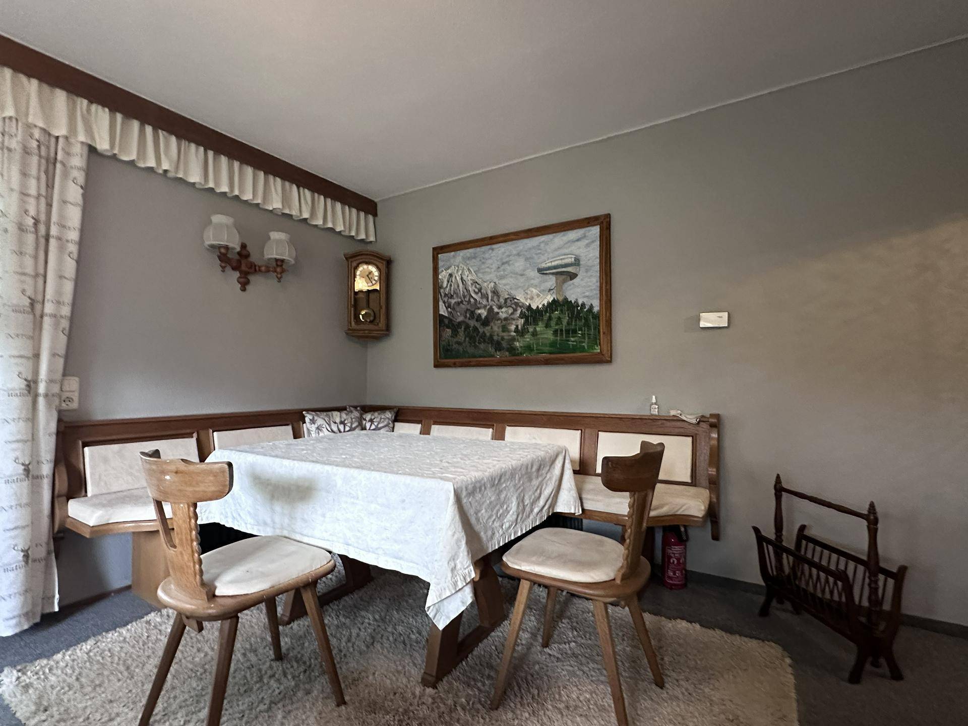 Gemütlicher Essbereich mit traditioneller Eckbank und Holztisch, dekoriert mit einem Wandbild.