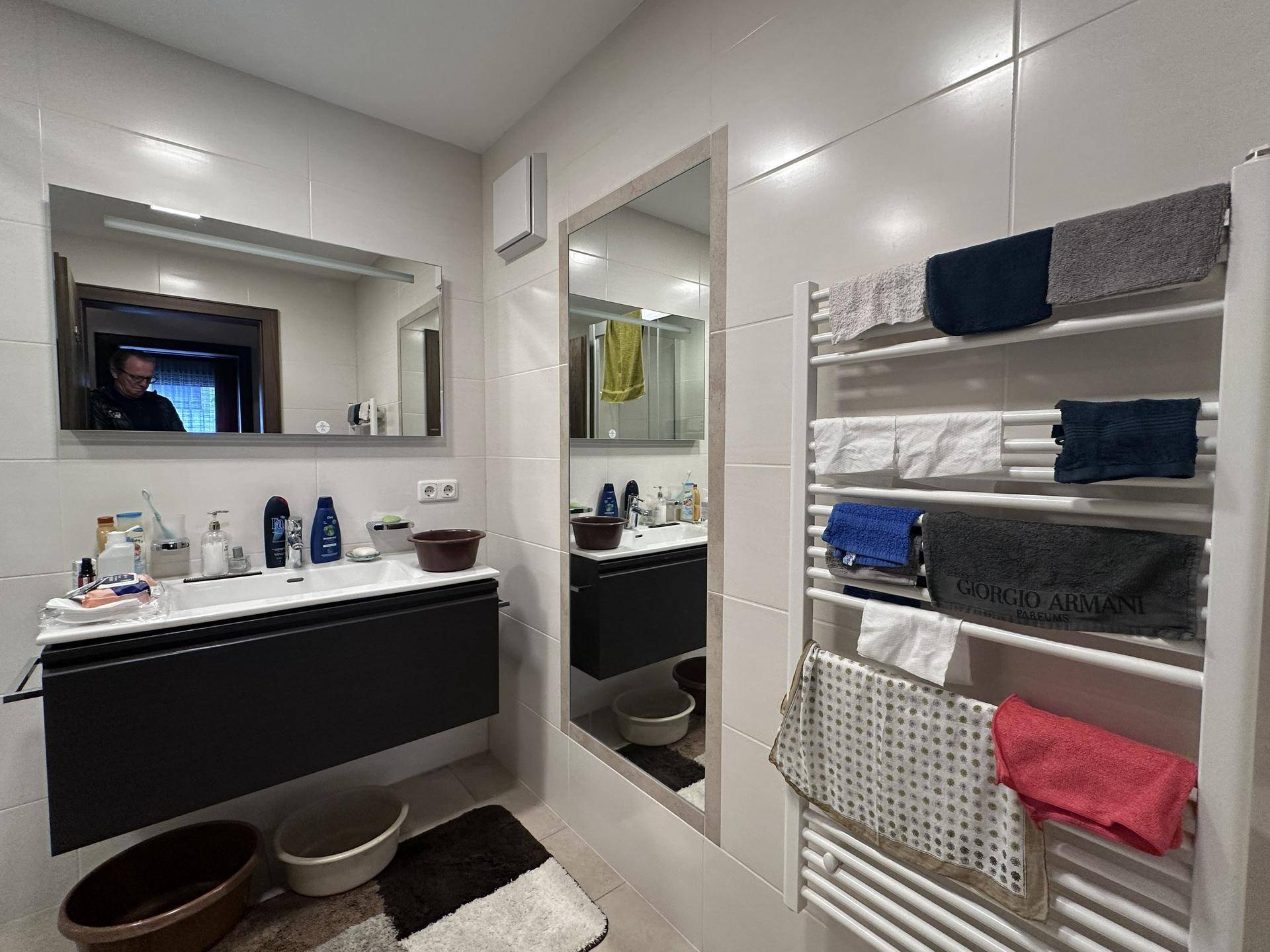 Modernes Badezimmer mit großem Waschtisch, Spiegeln und beheiztem Handtuchhalter.
