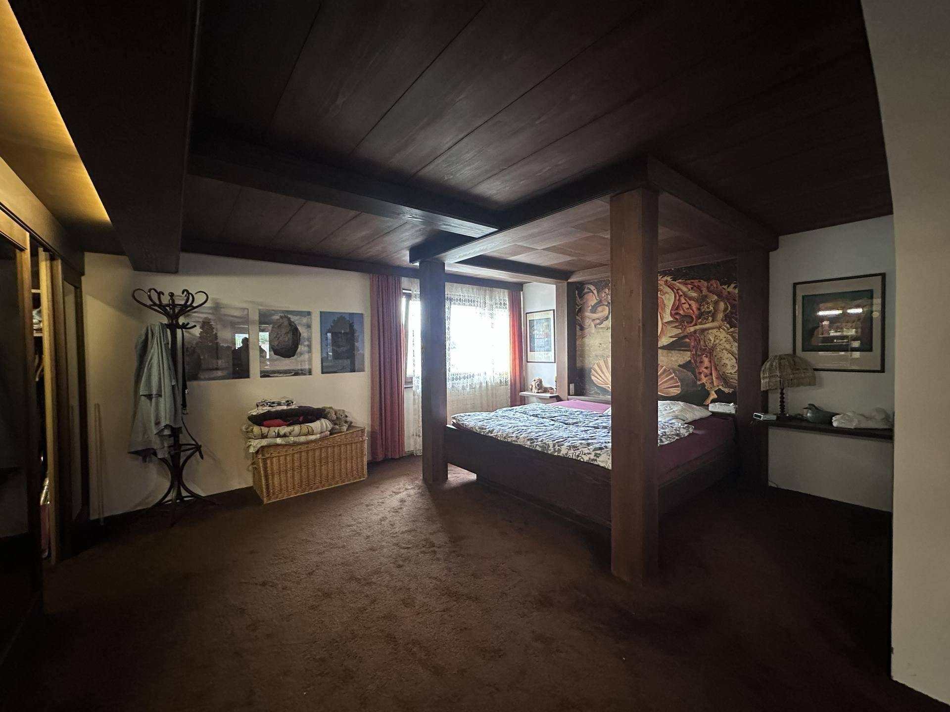 Traditionelles Schlafzimmer mit dunkler Holzbalkendecke, Teppichboden und einem Himmelbett.