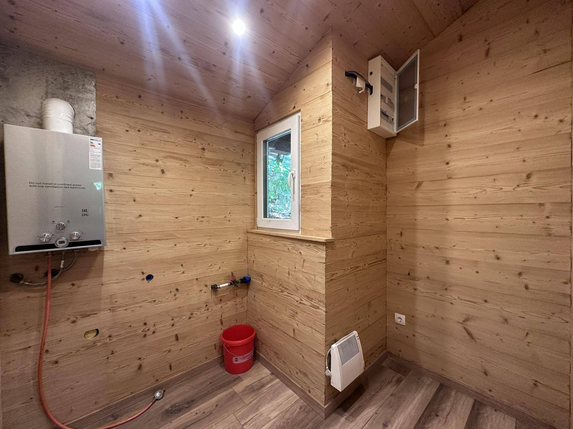Praktischer Hauswirtschaftsraum mit Warmwasserbereiter, Elektroverteilung und Fenster.