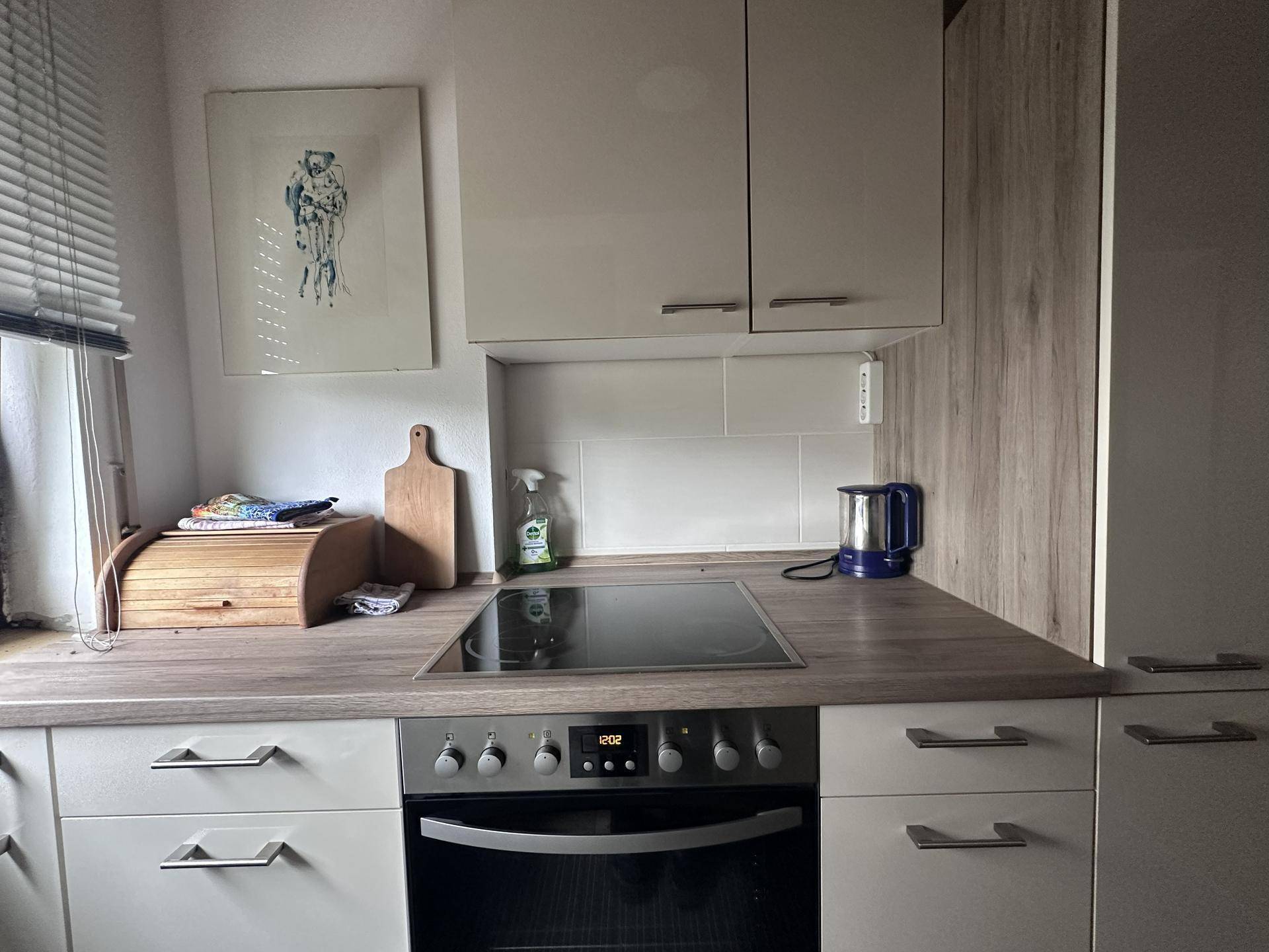 Küchenzeile mit hellem Holz-Look-Arbeitsplatte, Induktionskochfeld und Backofen.