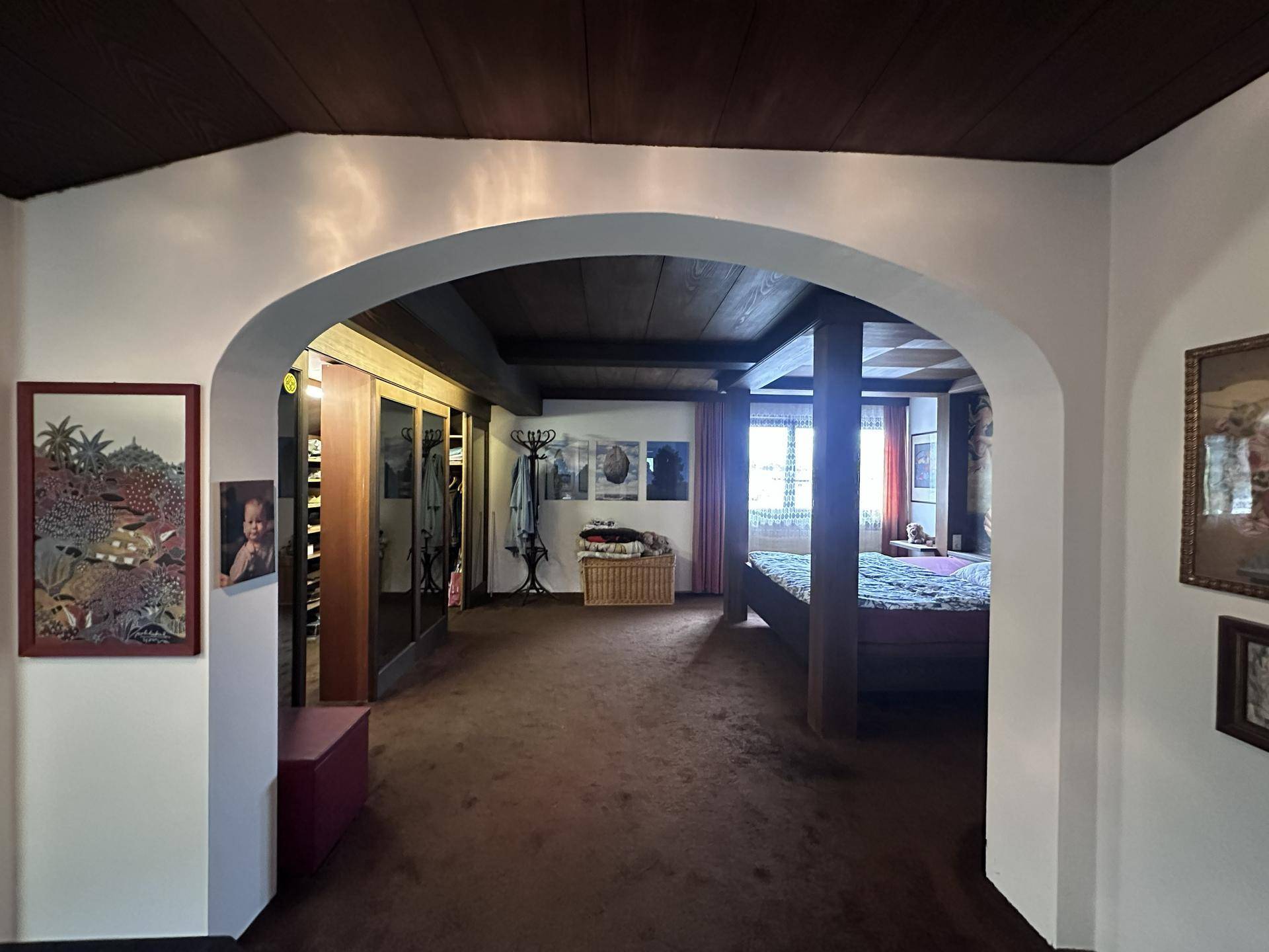 Geräumiges Schlafzimmer mit Holzbalkendecke, Teppichboden und integrierten Kleiderschränken.