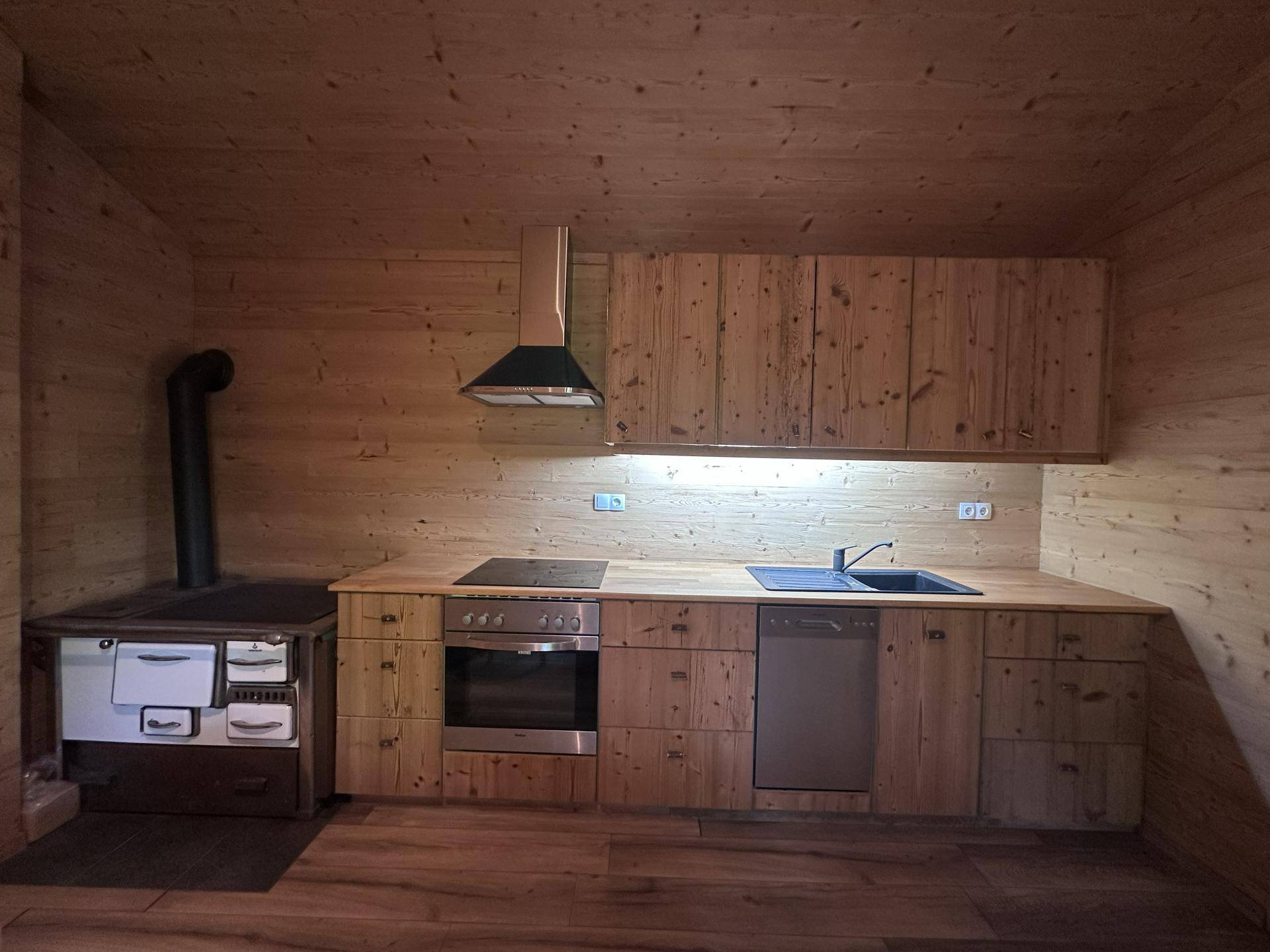 Voll ausgestattete Holzküche mit modernen Einbaugeräten und traditionellem Holzofen.