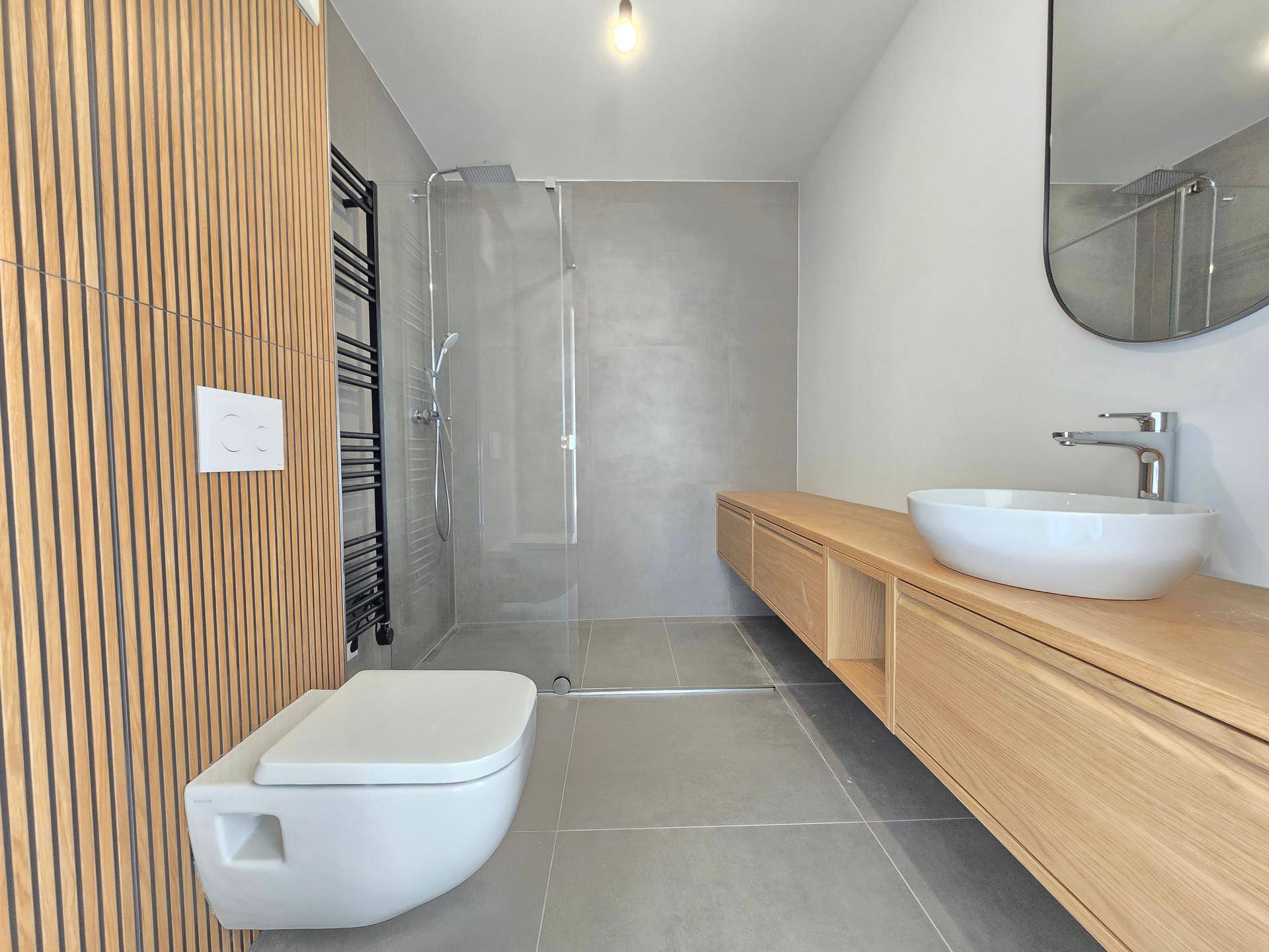 Modernes Badezimmer mit begehbarer Dusche, Holzwaschtisch und Wand-WC in minimalistischem Design.