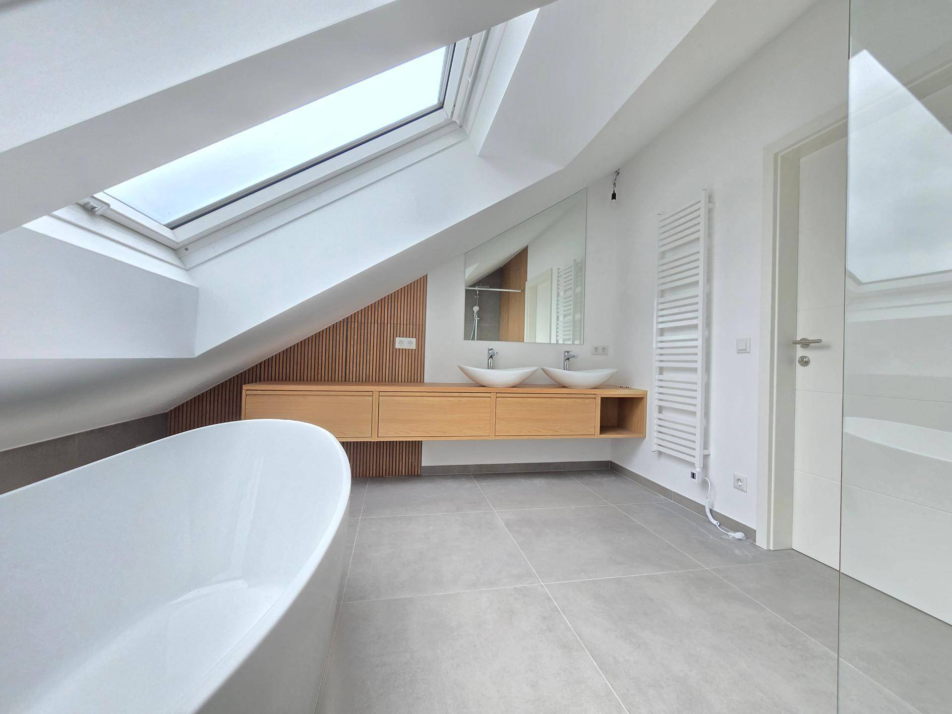 Luxuriöses Dachgeschossbad mit freistehender Badewanne, Doppelwaschbecken und großen Dachfenstern.