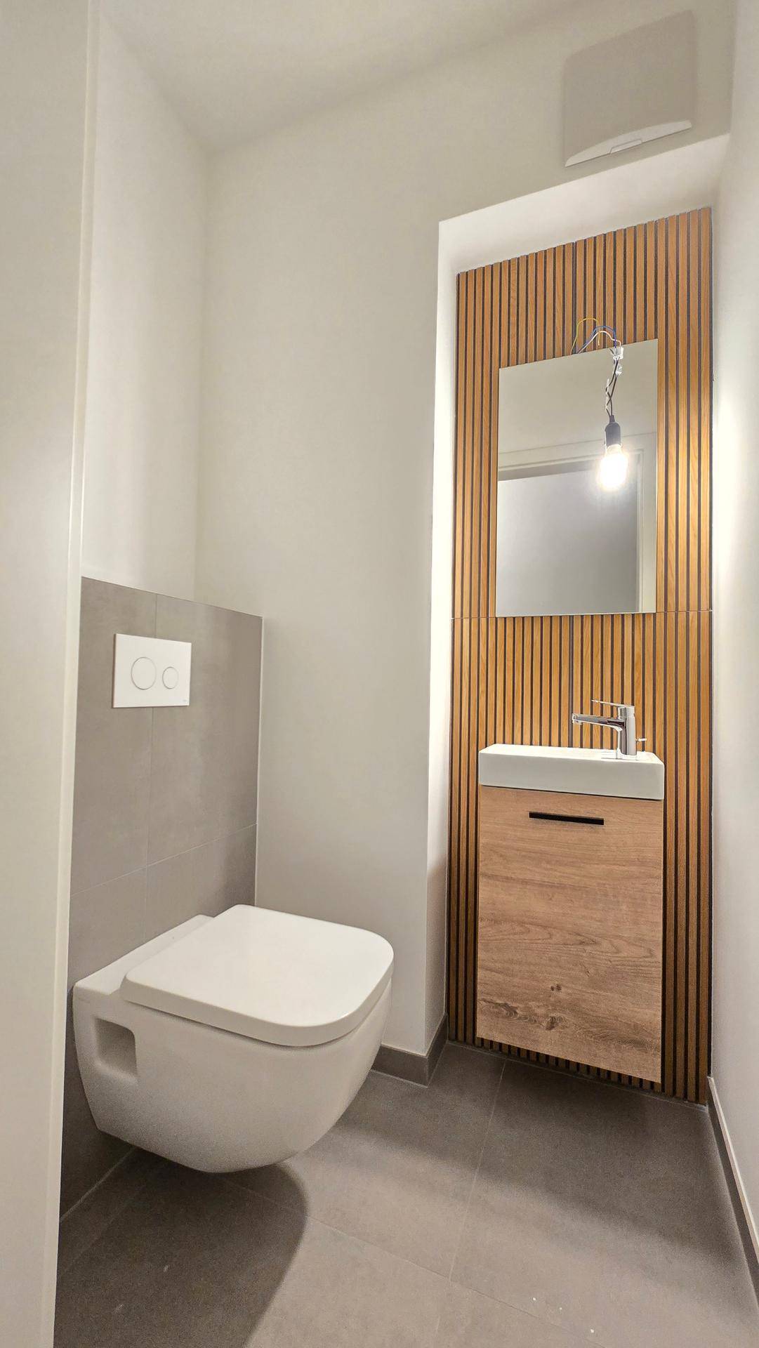 Kleines Gäste-WC mit wandhängender Toilette, modernem Waschbecken und Holzvertäfelung.