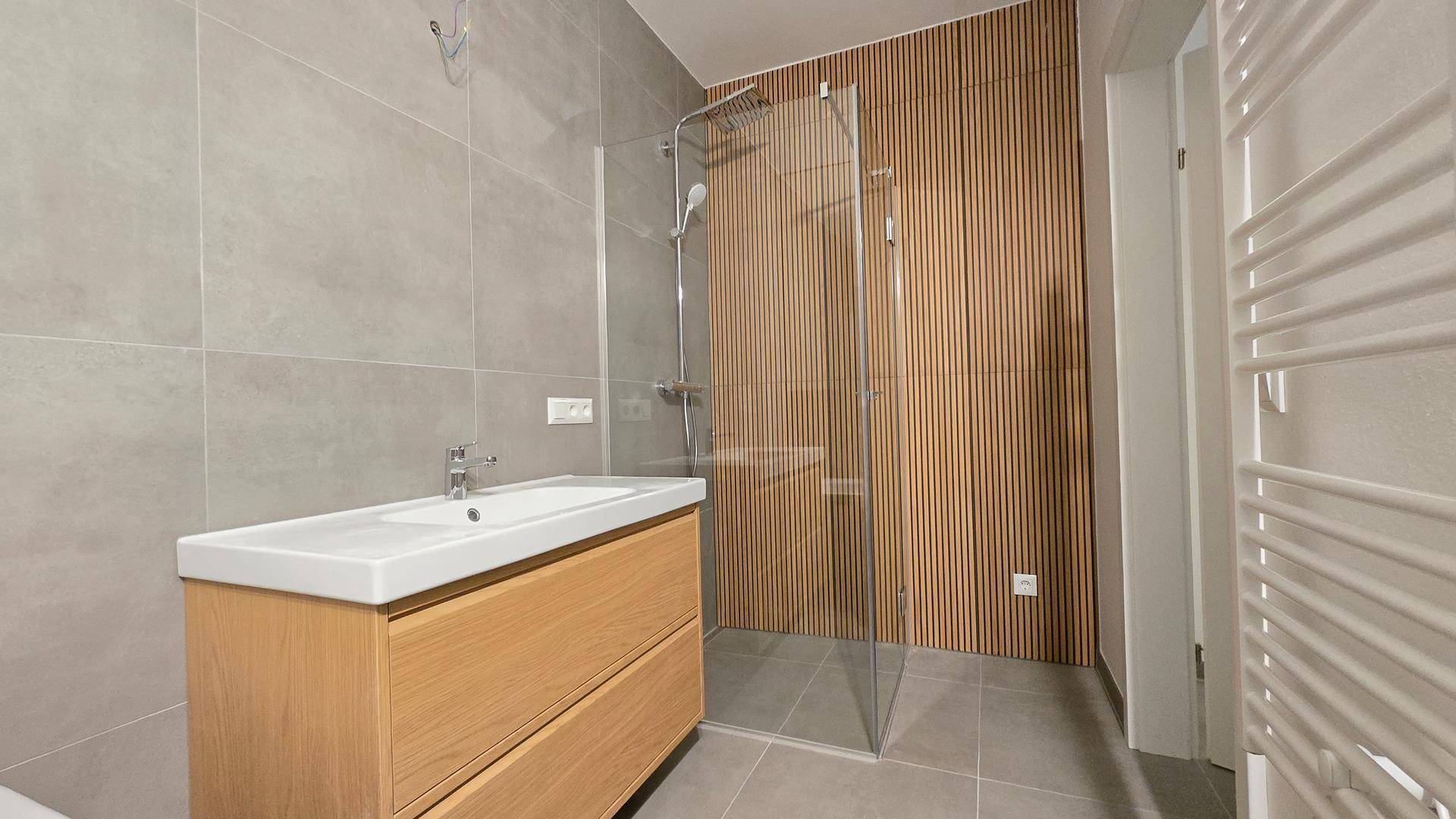 Modernes Badezimmer mit begehbarer Dusche, Holzvertäfelung und großformatigen Fliesen.