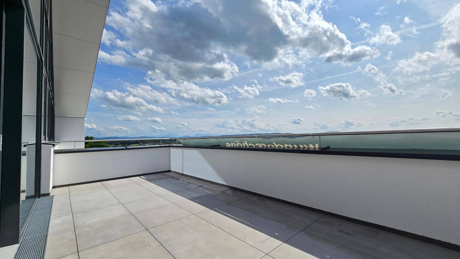 Moderne Terrasse mit Glasgeländer und Panoramablick auf die weite Landschaft und den Horizont.