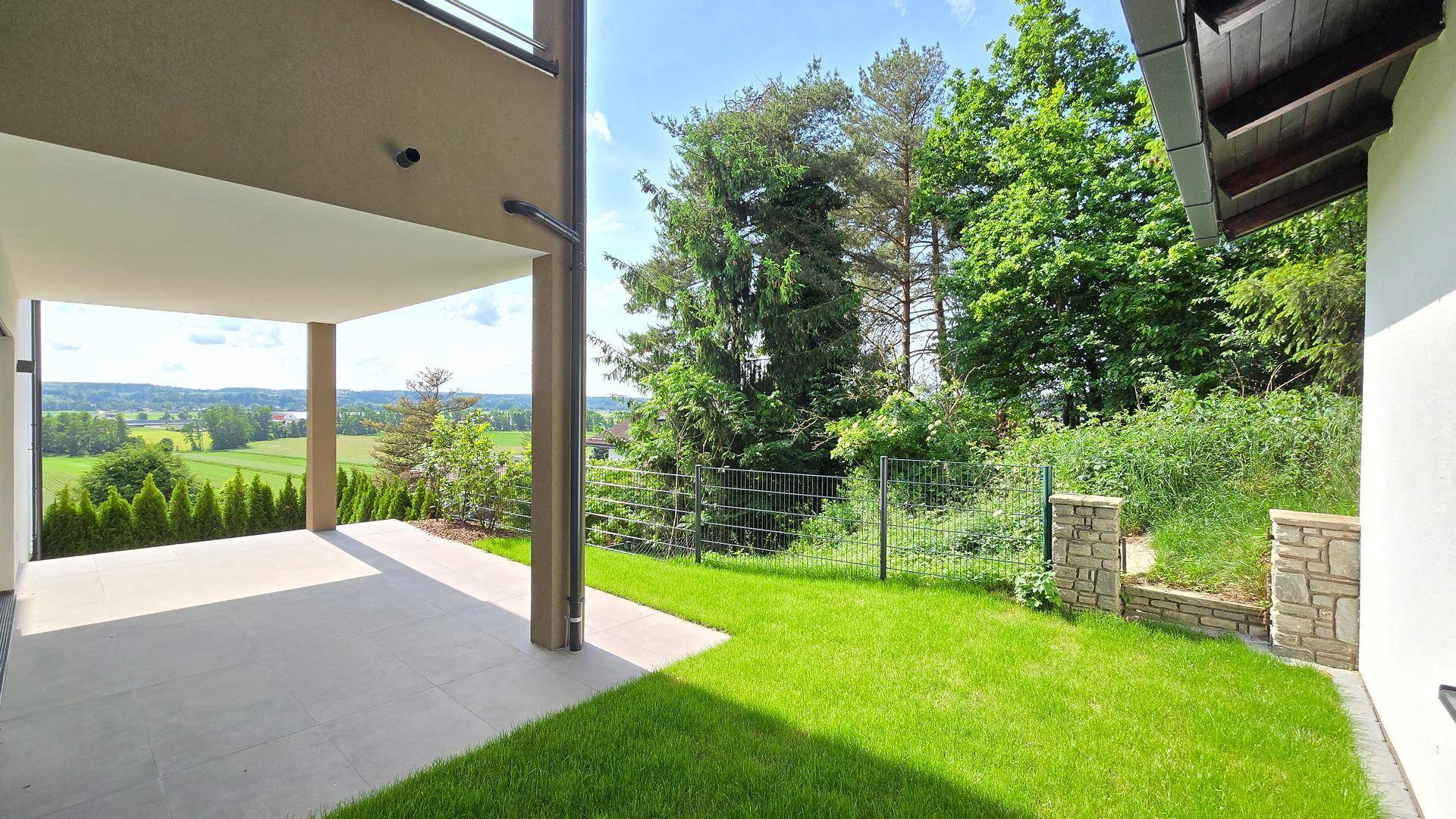 Geräumige überdachte Terrasse mit Rasen und Panoramablick über die idyllische Landschaft.