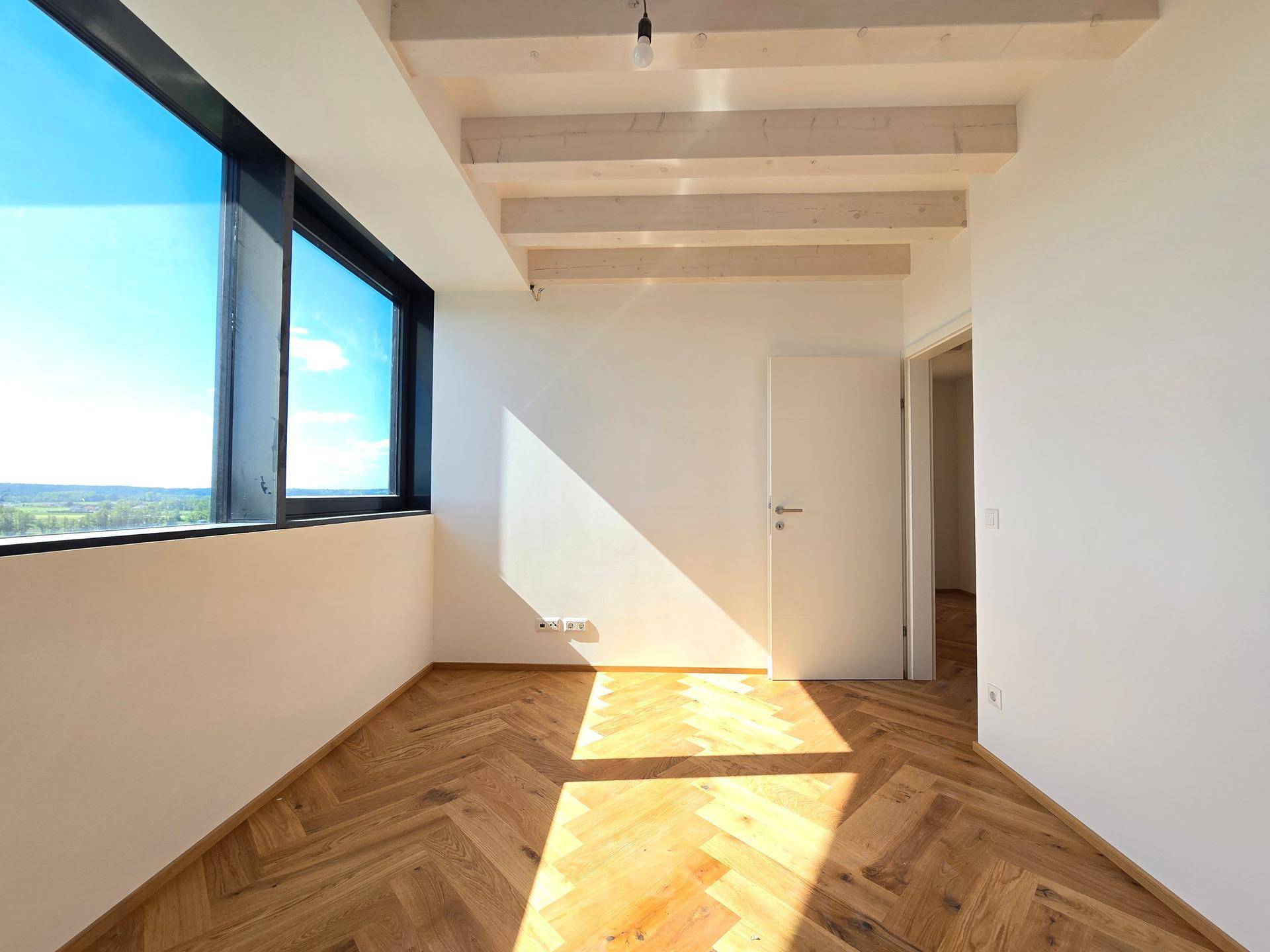 Schlafzimmer mit Fischgrätparkett, großen Fenstern und viel Sonnenlicht, bietet einen weiten Ausblick.