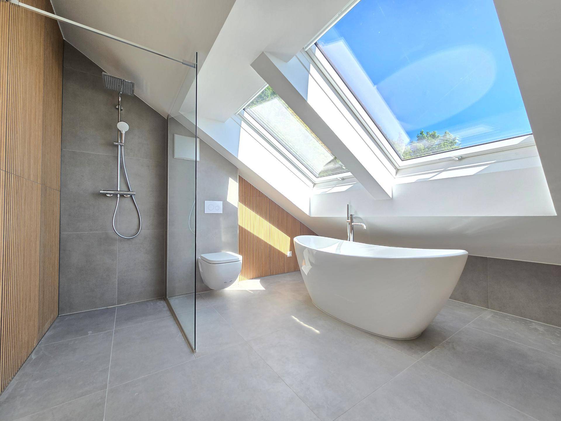 Helles Dachgeschossbad mit begehbarer Dusche, freistehender Badewanne und großen Dachfenstern.
