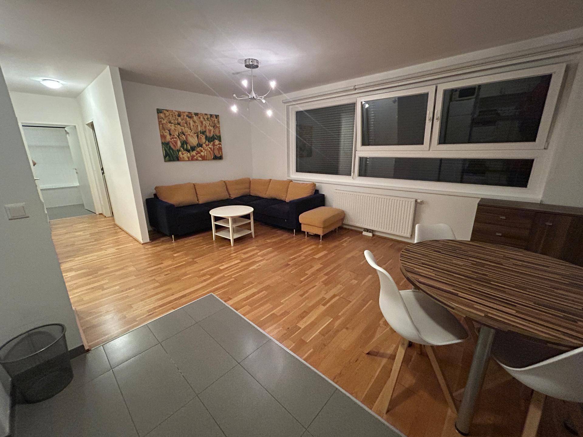 Geräumiger Wohn-Essbereich mit Holzparkettboden, bequemer Eckcouch und Esstisch am Fenster.