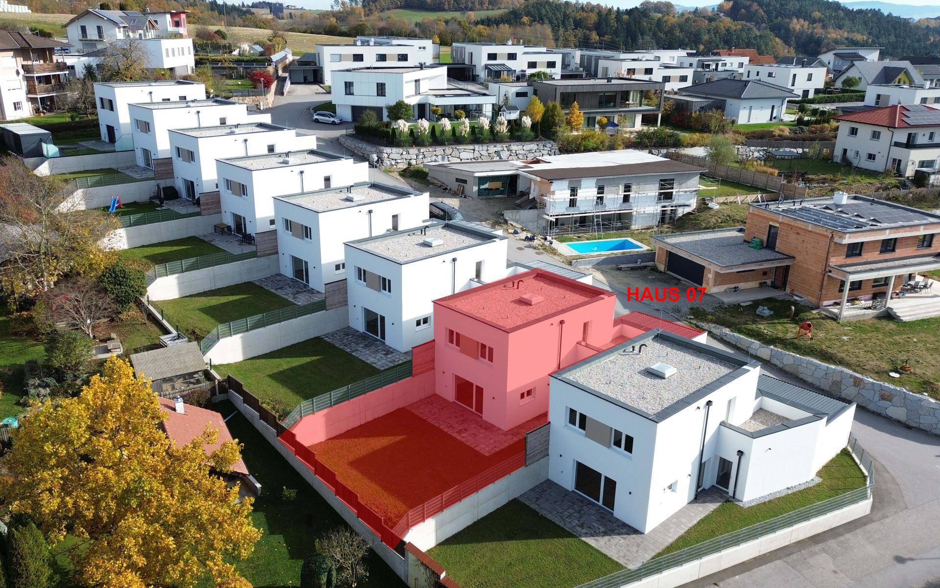Luftaufnahme einer modernen Wohnsiedlung mit Neubauten und einem hervorgehobenen Haus.