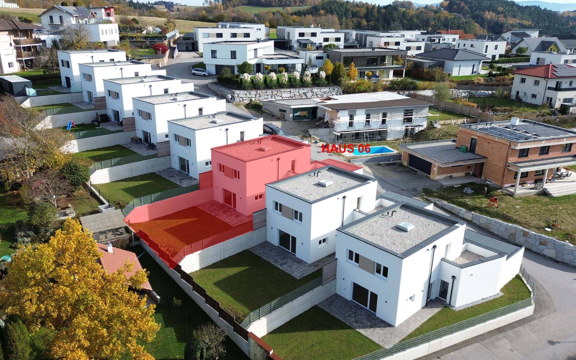 Luftaufnahme einer modernen Wohnsiedlung mit Neubauten und viel Grünfläche, Haus 06 ist markiert.