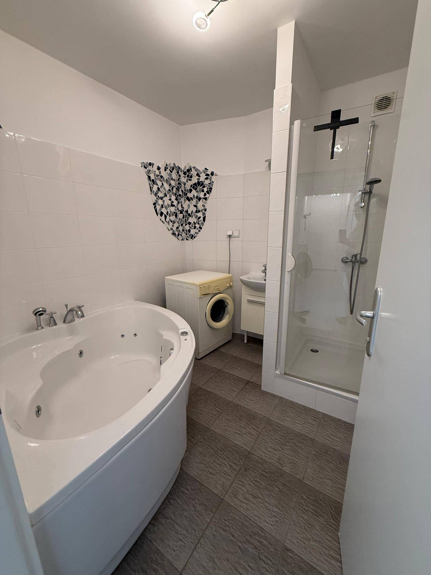 Badezimmer mit Eckbadewanne, Duschkabine und Waschmaschine.