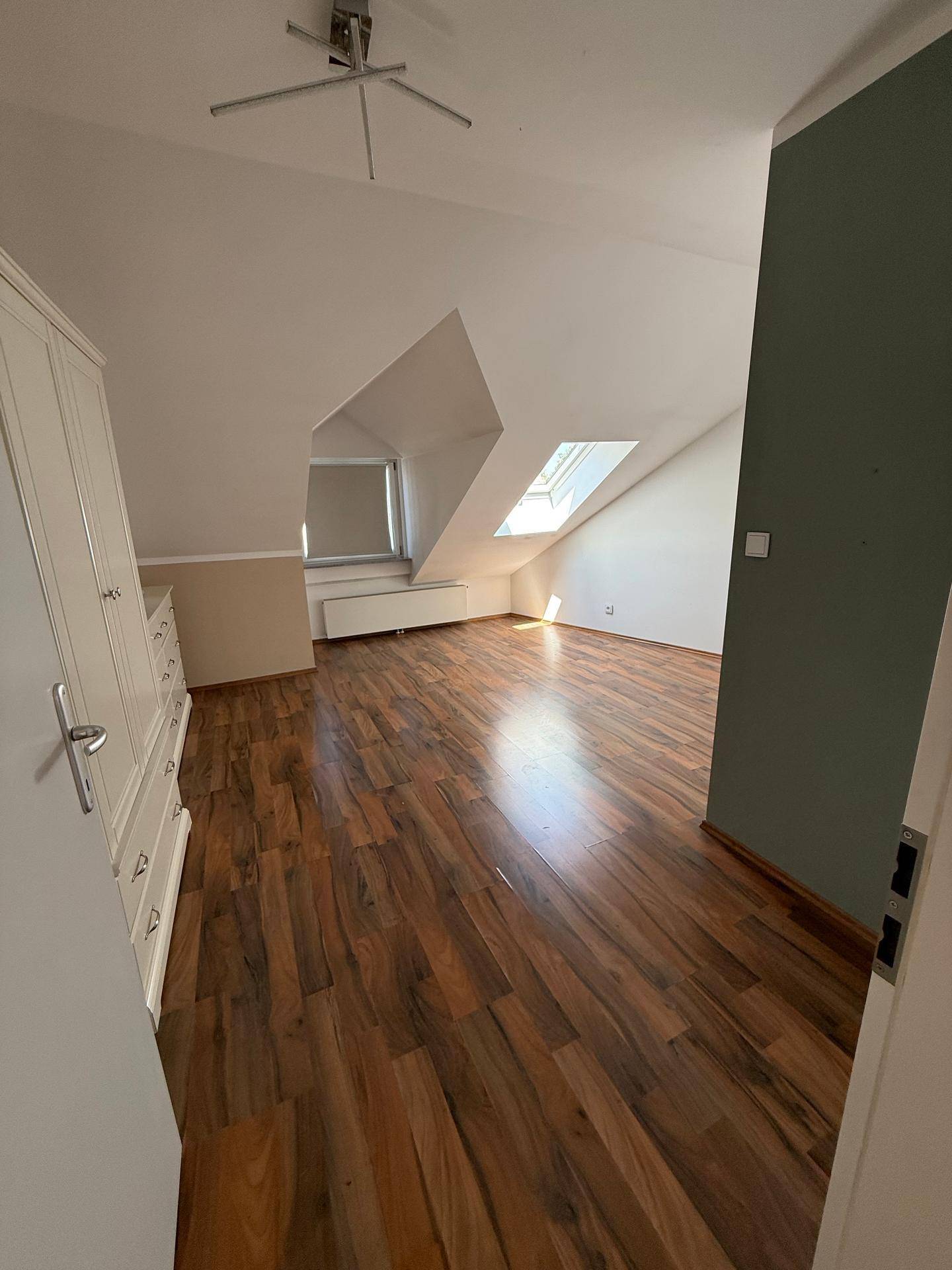 Schlafzimmer mit Laminatboden, Dachschrägen und zwei Dachfenstern.