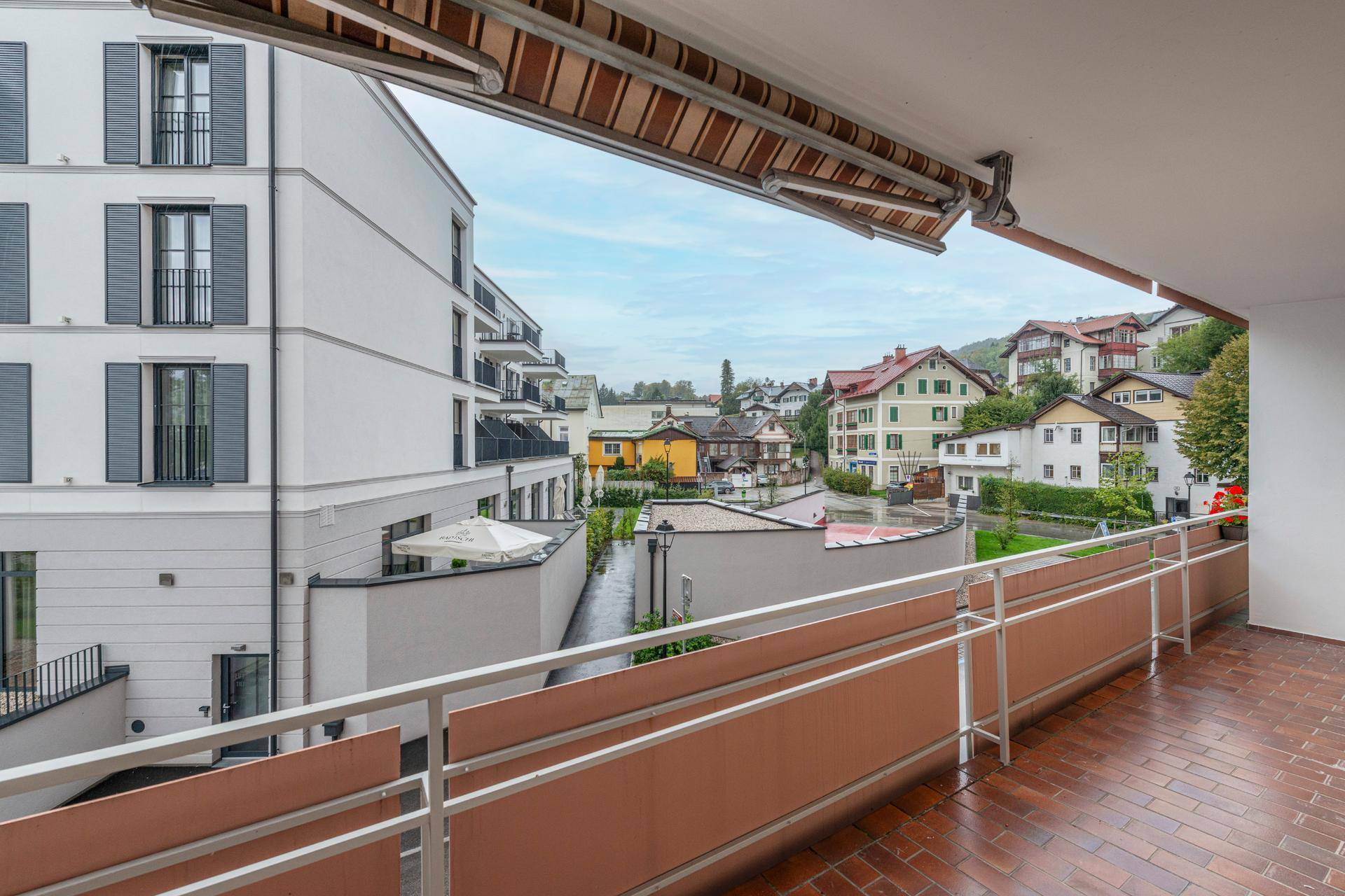 Großer Balkon mit Markise und Blick auf die umliegenden Gebäude und Hügel.
