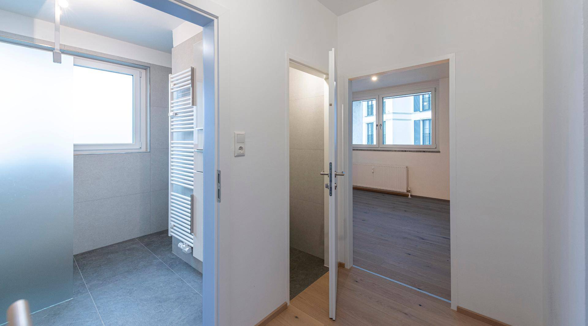 Heller Flur mit Parkettboden, der zum Badezimmer und einem weiteren Zimmer führt.