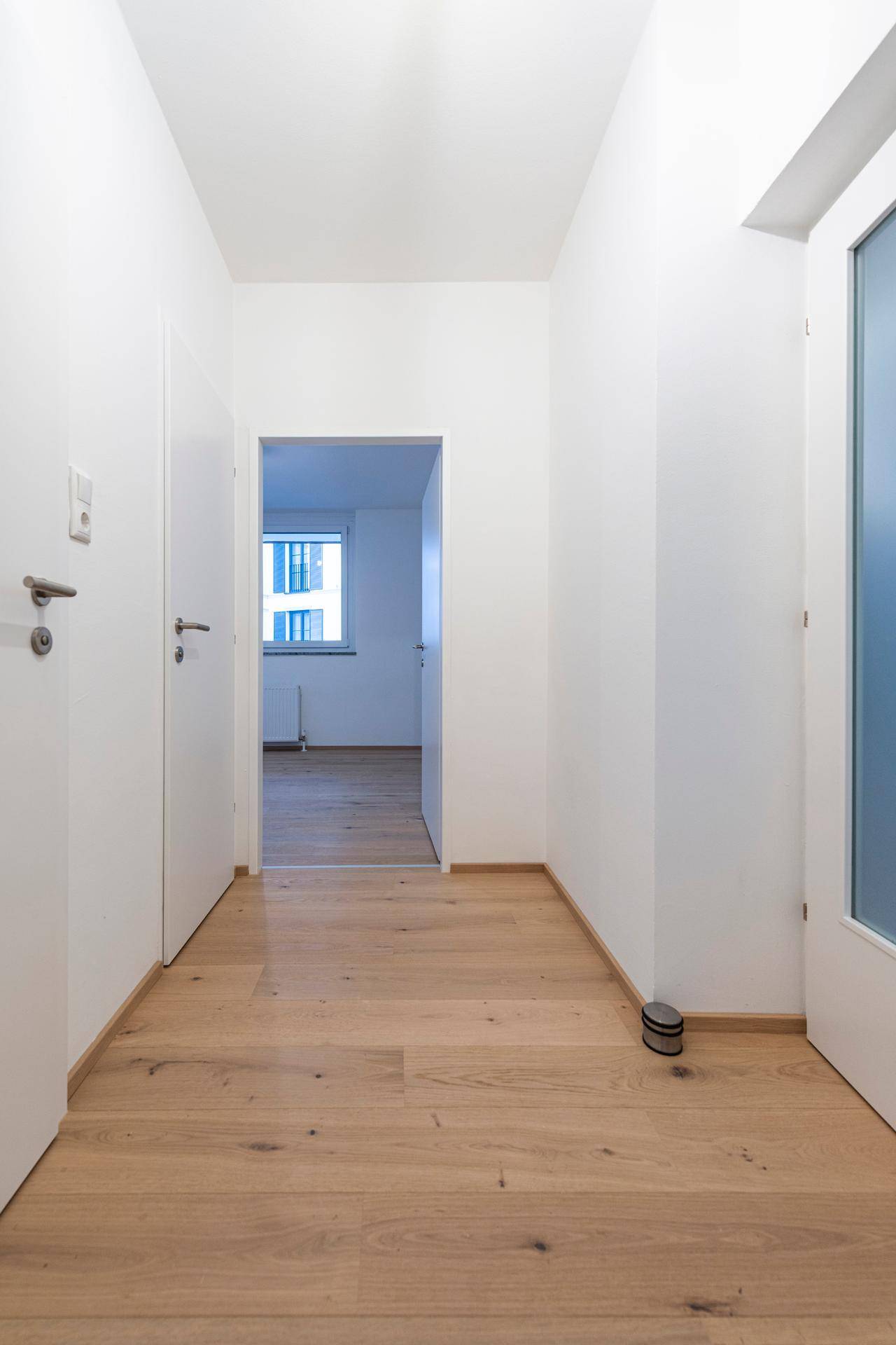 Geräumiger Flur mit Parkettboden und Blick in ein weiteres Zimmer.