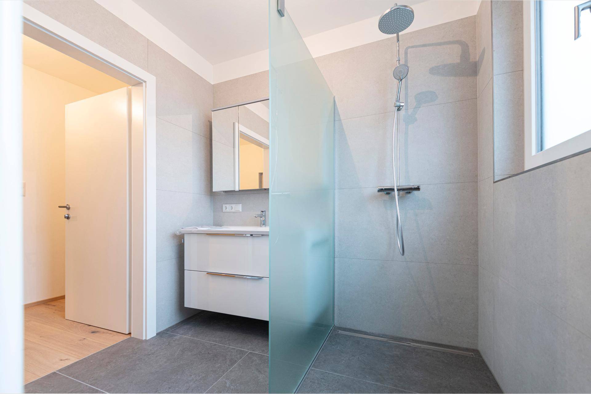 Zeitgemäßes Badezimmer mit ebenerdiger Dusche und modernem Waschtisch.