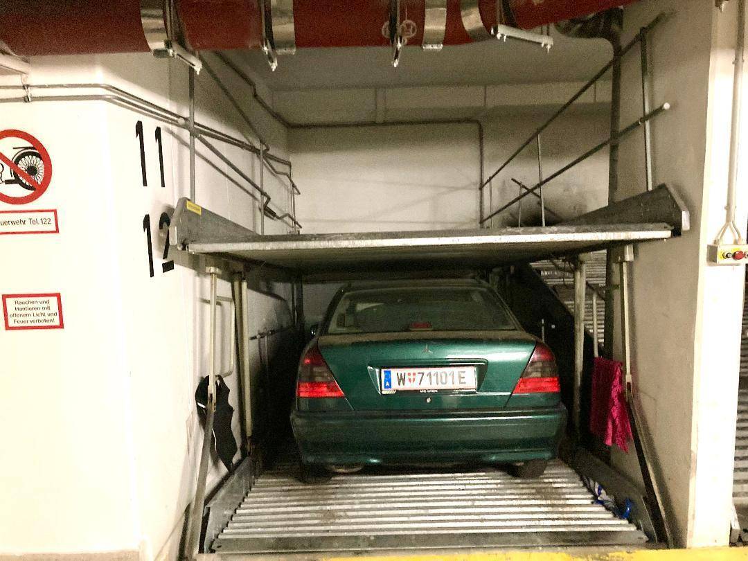 Grünes Fahrzeug auf einem hydraulischen Parklift in einer Tiefgarage geparkt.