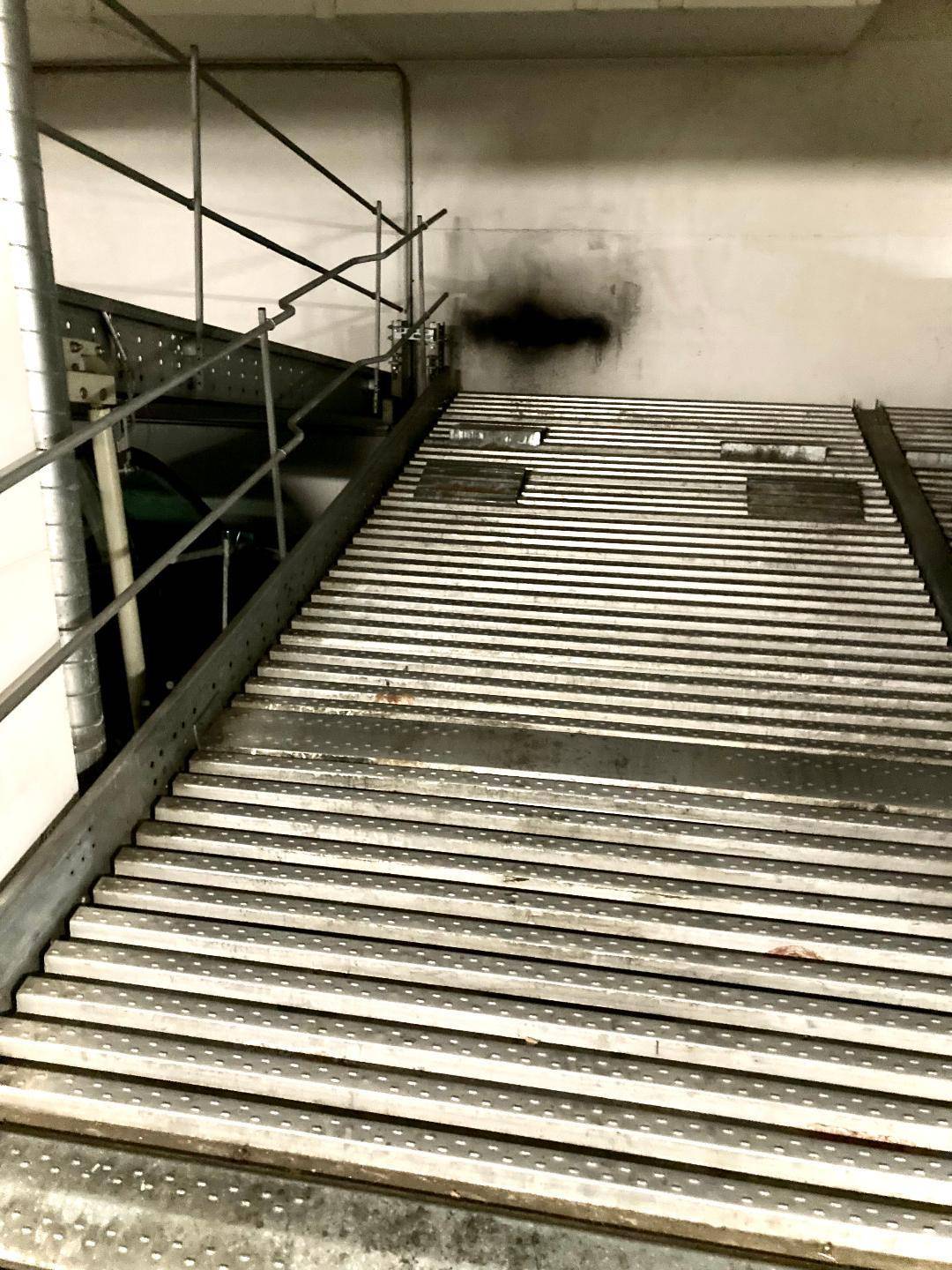Nahaufnahme einer mechanischen Parkrampe mit Metallstruktur in einer Tiefgarage.