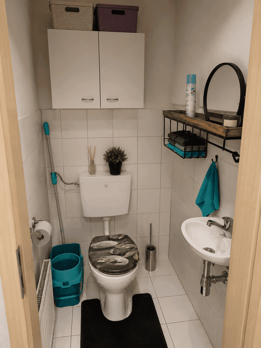 Kleines Gäste-WC mit Toilette, Waschbecken und Wandschränken, funktional eingerichtet.