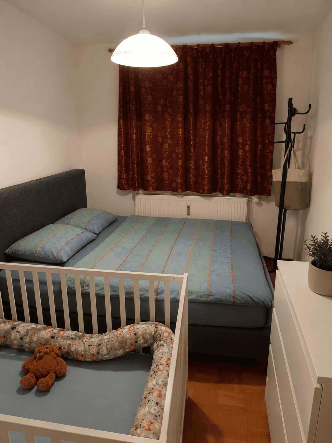 Gemütliches Schlafzimmer mit Doppelbett und Babybett, ideal für junge Familien.