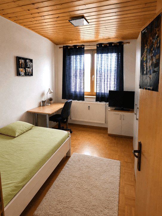 Gemütliches Schlafzimmer mit Einzelbett, Schreibtisch und Fernseher, ideal für Kinder oder Gäste.
