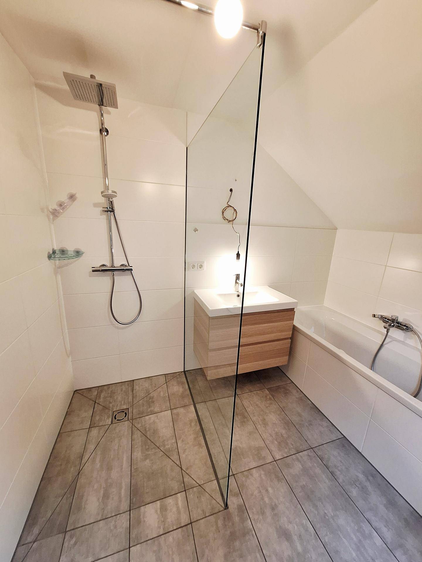 Geräumiges Badezimmer mit begehbarer Dusche, Badewanne und modernem Waschtisch unter Dachschräge.